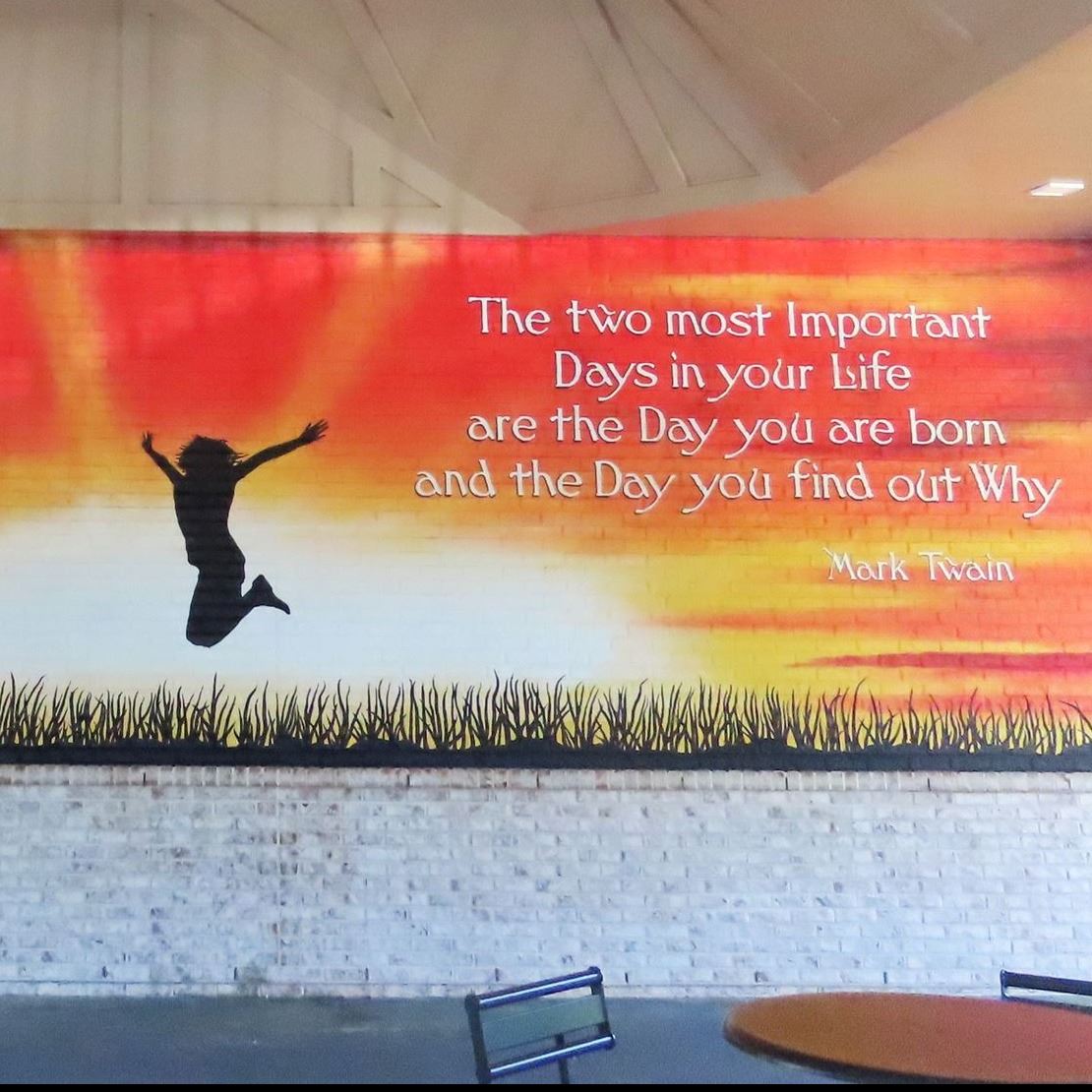 Mural of sunset with silhouette of woman jumping and Mark Twain Quote