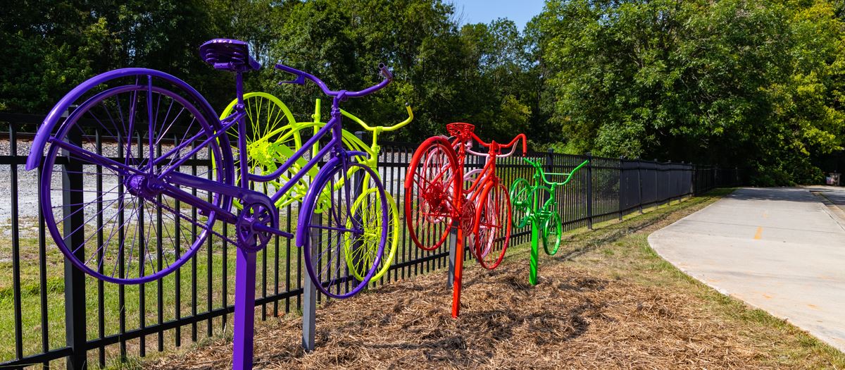 scultpure of 5 painted bicycles, one each in purple, red, orange, yellow, green