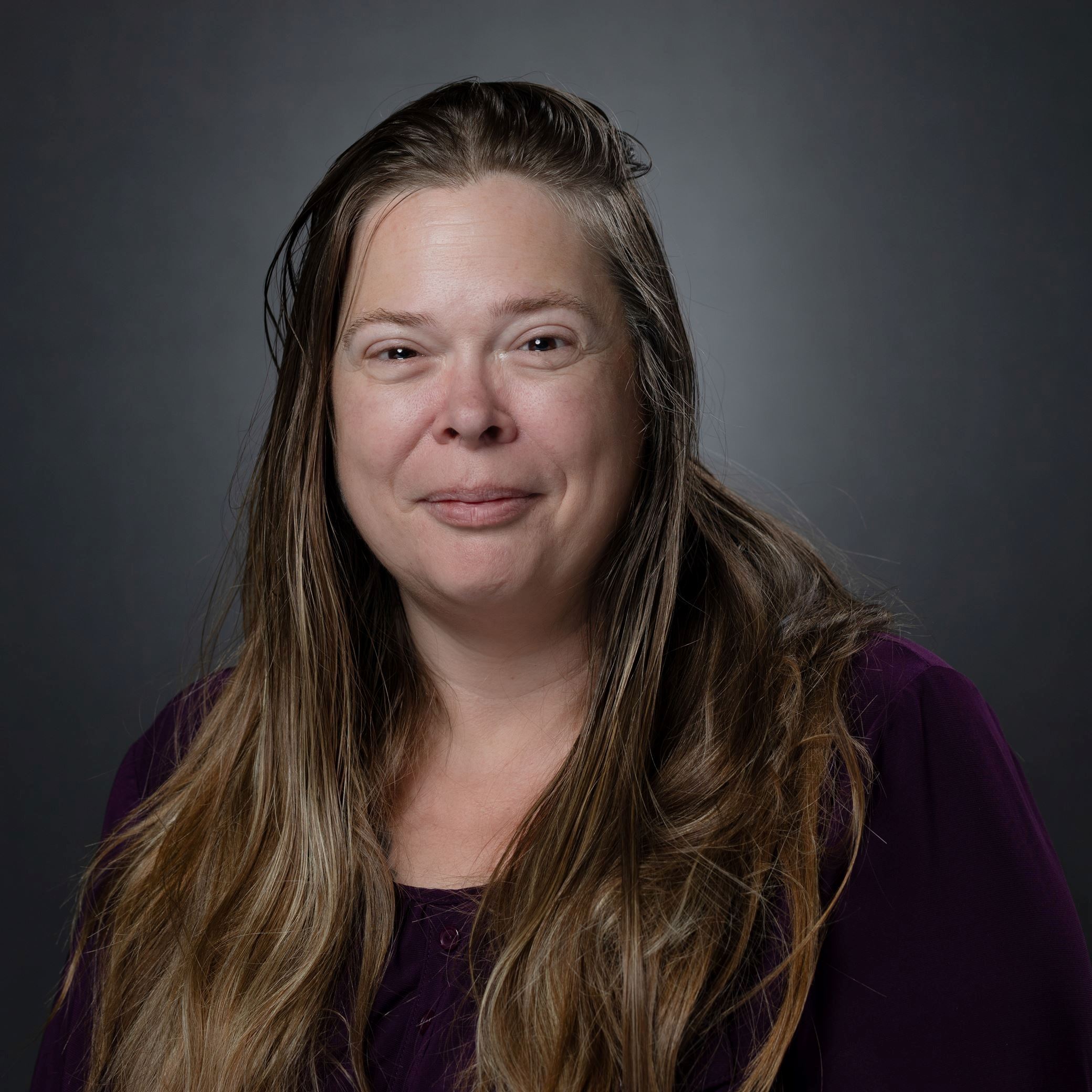 Headshot of Therese Brown female with long dark blonde hair wearing purple shirt
