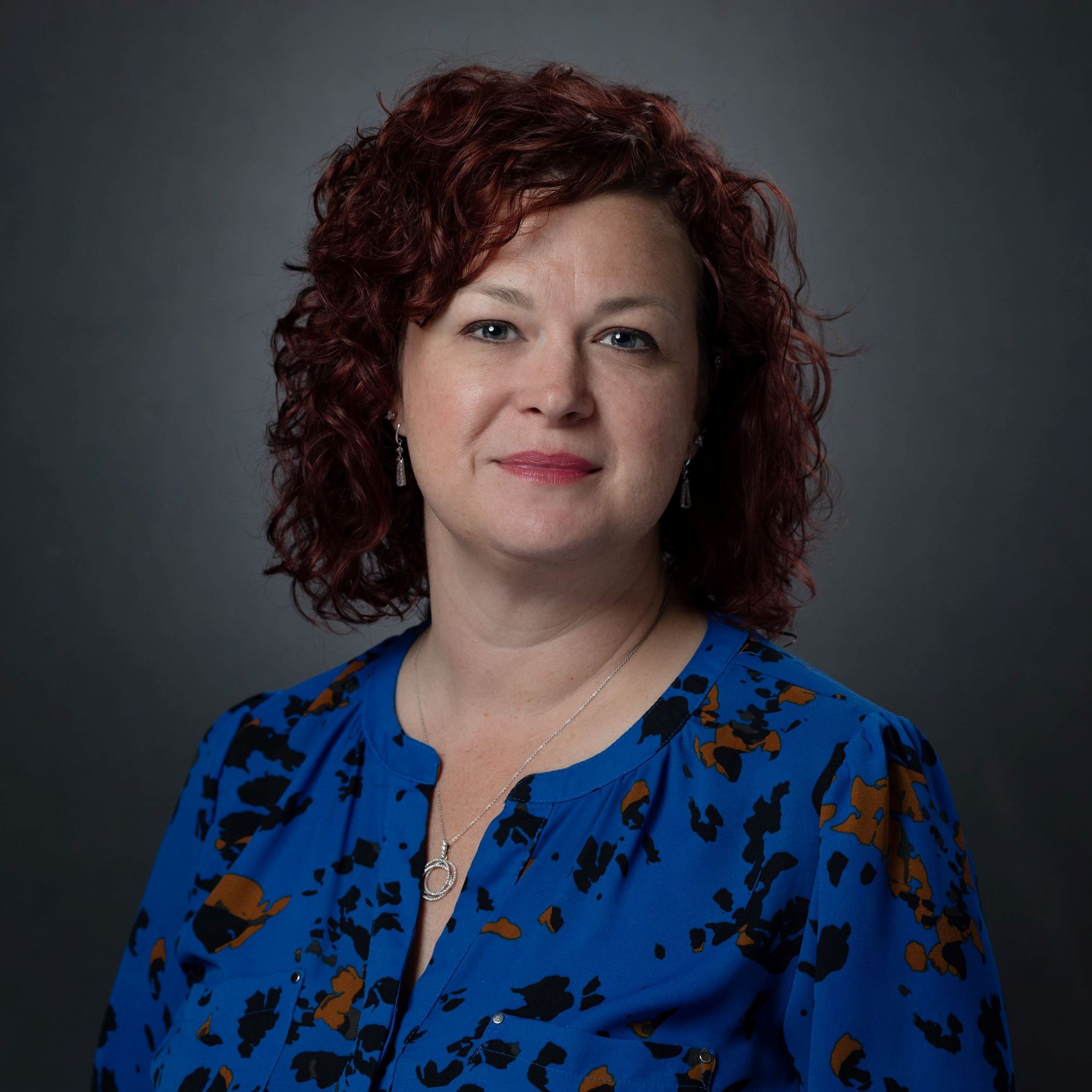 Headshots of Rebecca Baumann female with short brown curly hair wearing blue blouse