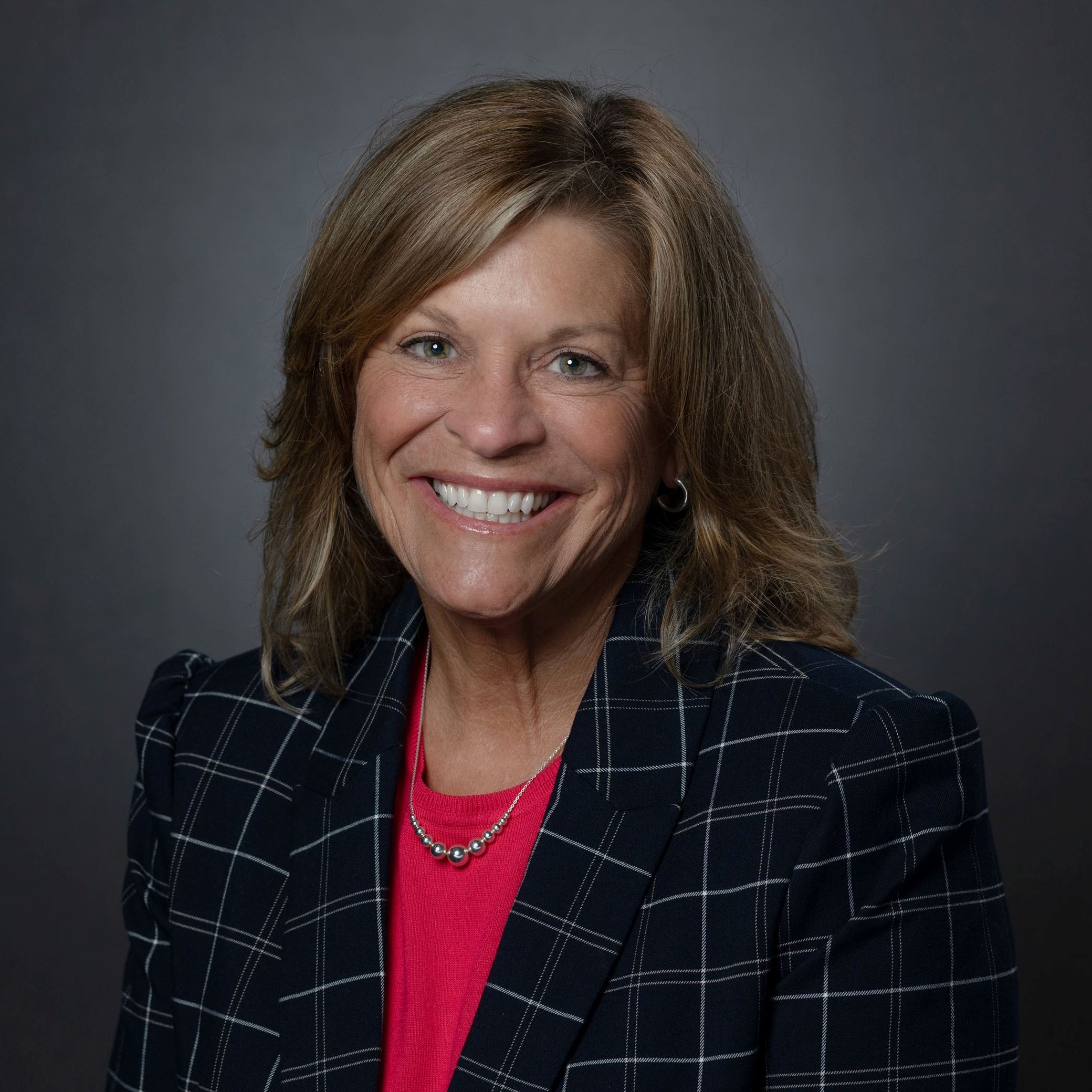 Headshot of Jill Minnoia female with shoulder length blonde hair wearing plaid blazer