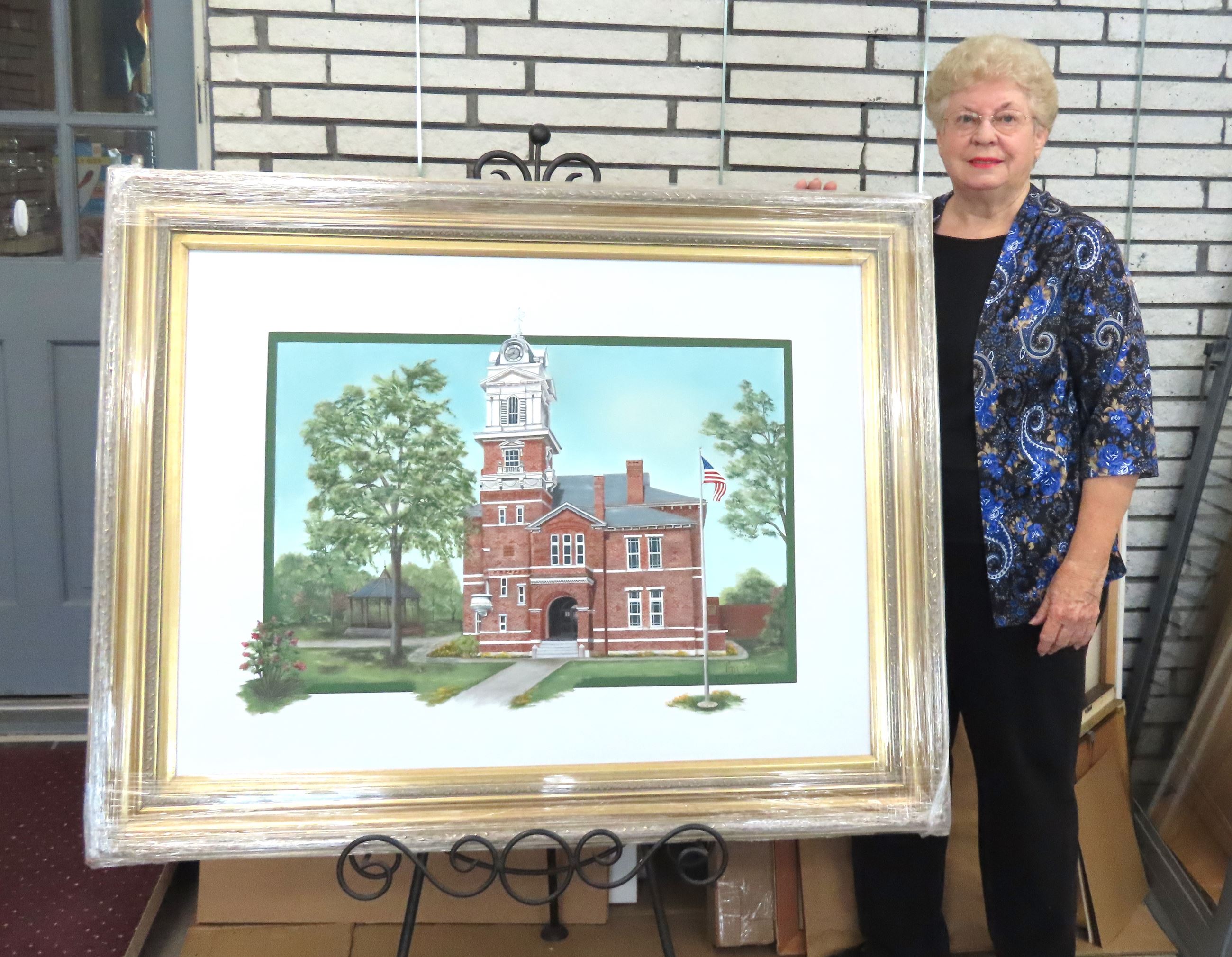 older woman with glasses standing next to painting on easel, height reaches her shoulder